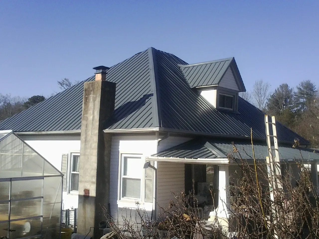 Dark blue standing seam metal roof on a white farmhouse with dormer — Slate & Tile Roof Repair by Roofing Brothers in Modoc