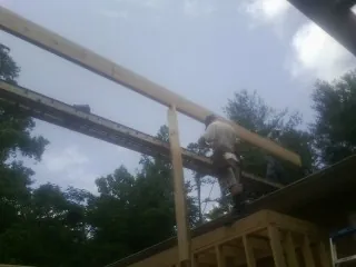 Carpenter setting a ridge beam over a new addition frame — Ice Dam Removal by Roofing Brothers in Modoc